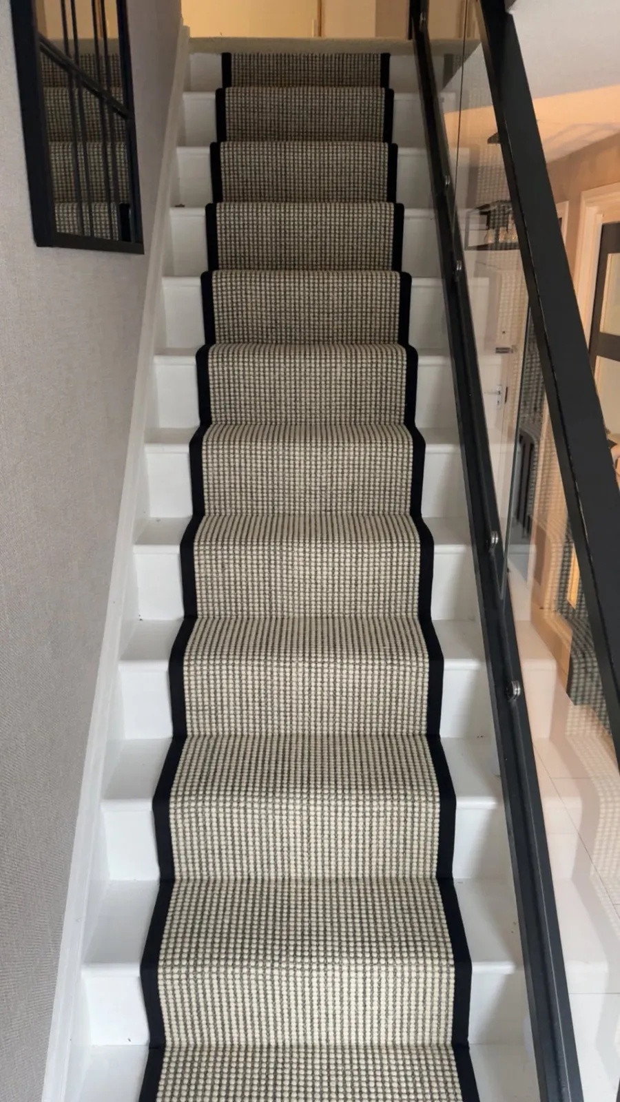 Neutral textured stair runner with black edging fitted on white stairs