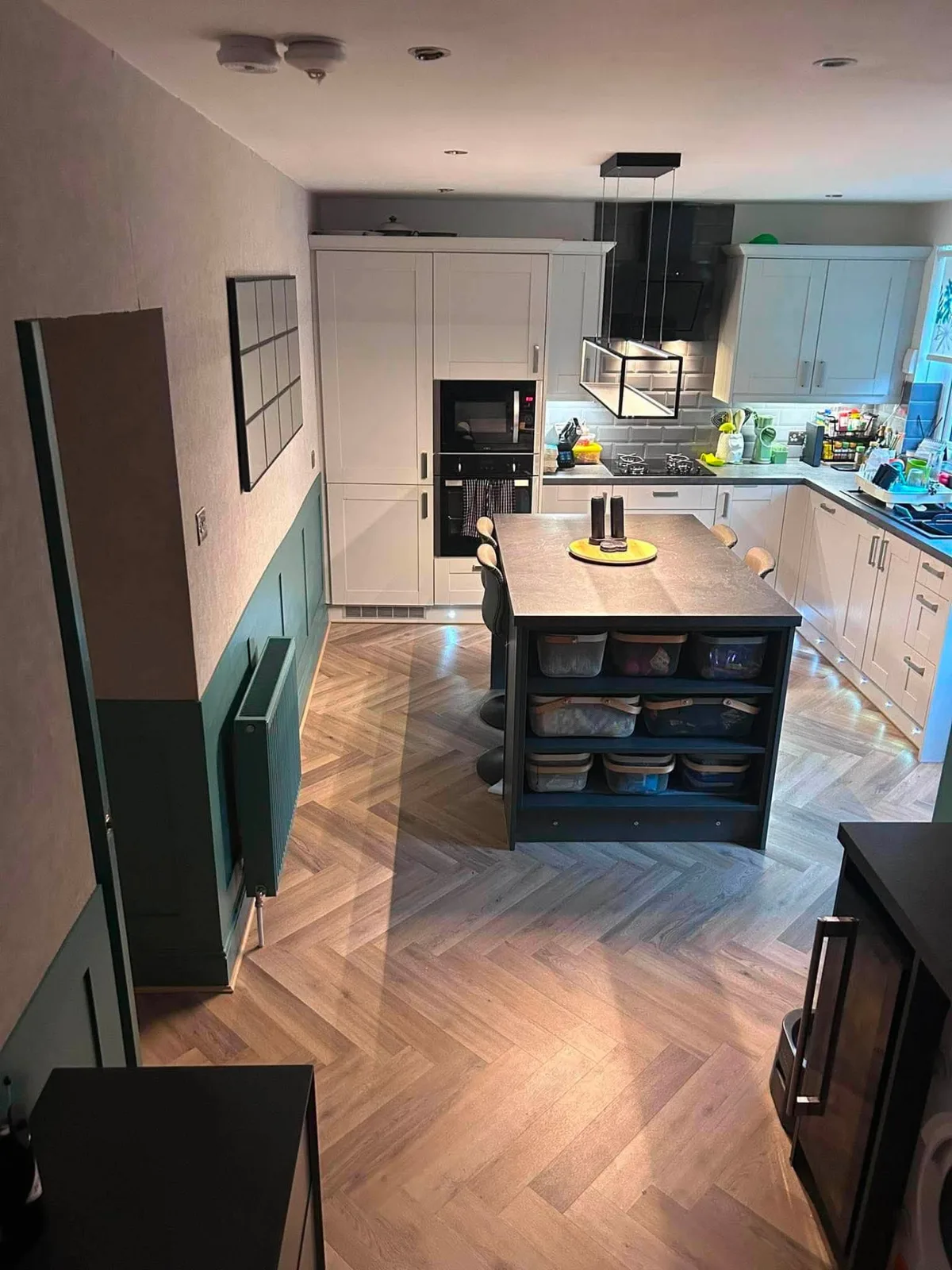 Open-plan kitchen with a herringbone wood-effect floor laid around a central island